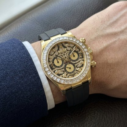 Yellow gold chronograph with a pavé leopard dial on its black rubber strap, worn on the wrist below a dark suit cuff