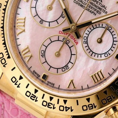Macro of the pink mother-of-pearl dial, its gold Roman numerals, three pink counters ringed in gold and the black tachymeter scale