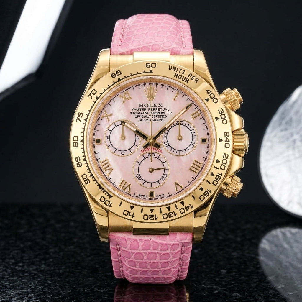 Gold-tone chronograph with a pink mother-of-pearl dial on a pink lizard-grain strap, worn on the wrist below a navy suit cuff