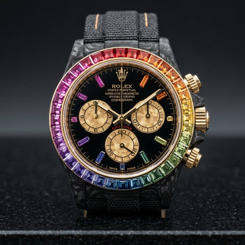Black forged carbon chronograph with a gold-set rainbow stone bezel and a black dial, upright on polished black granite
