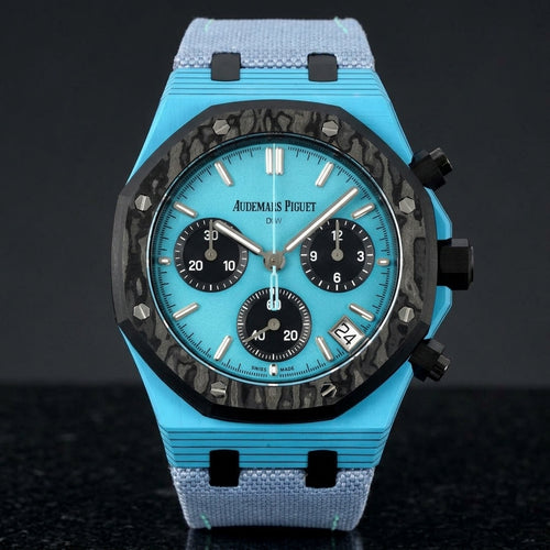 Octagonal chronograph with a sky-blue case, a black forged-carbon bezel and a sky-blue dial, upright on polished black granite