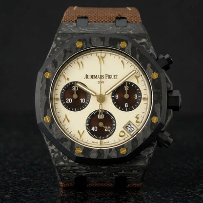 Black forged-carbon octagonal chronograph with a cream dial on its brown canvas strap, worn on the wrist below a dark suit cuff