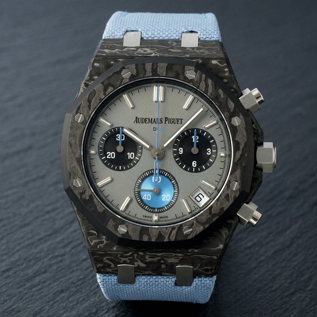 Black forged-carbon octagonal chronograph at a three-quarter angle on dark slate, whitish carbon veining on its flank beside the steel crown and pushers