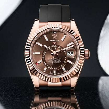 Rose-gold dual-time watch standing on dark stone, its black rubber strap curving away behind the case