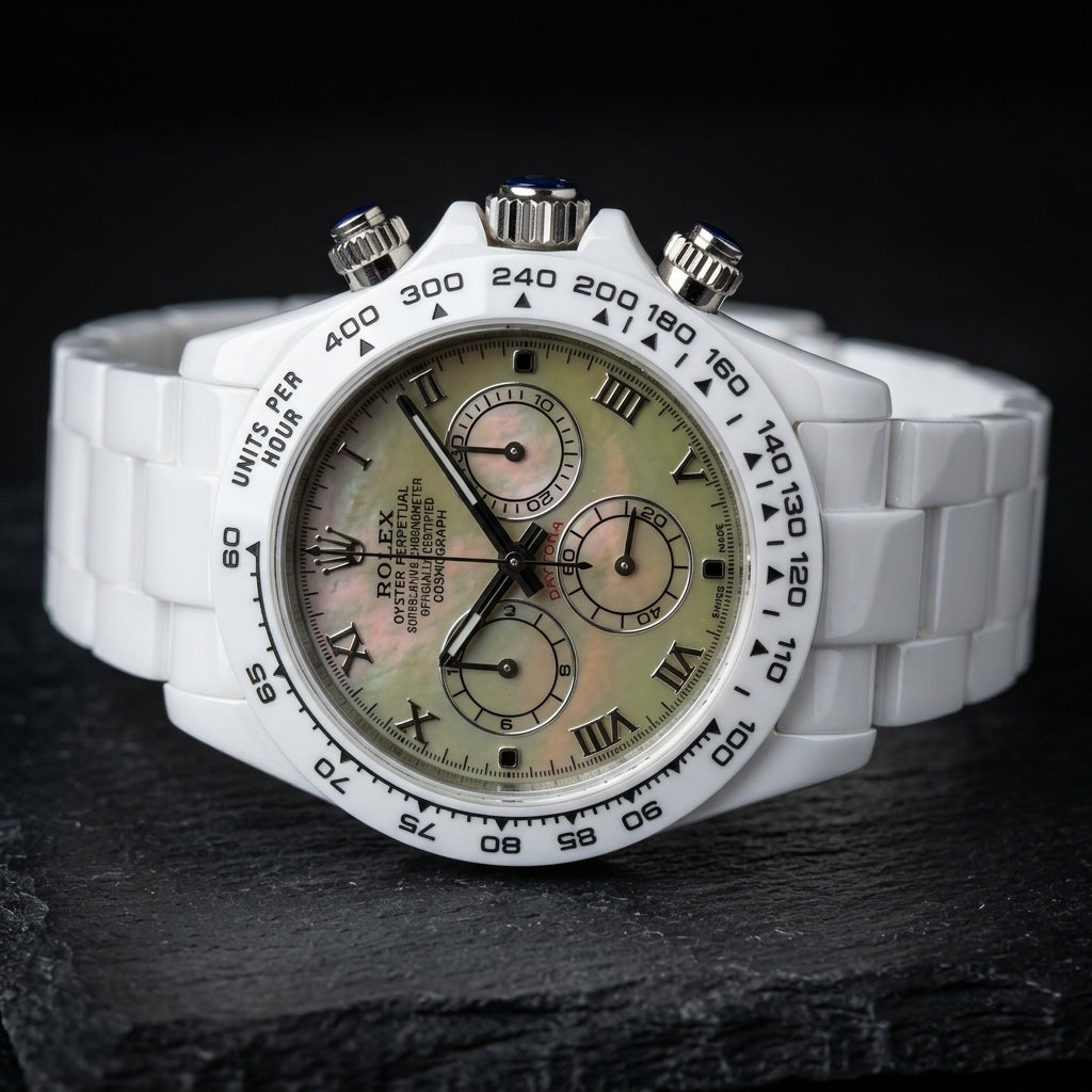 White ceramic chronograph at a three-quarter angle, the steel crown and pushers capped with deep-blue stones