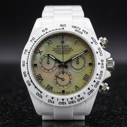 White ceramic chronograph with a green mother-of-pearl dial on the wrist below a dark suit cuff
