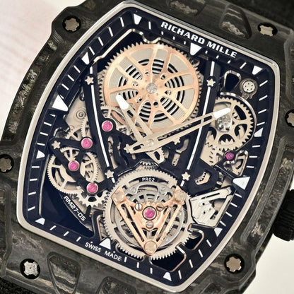 Macro of the open skeleton dial framed in black carbon: rose-gold spoked wheel, pink jewels and the tourbillon-style cage at six