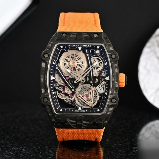 Black thin-ply carbon tonneau watch with an open skeleton dial and an orange woven strap, upright on polished black granite