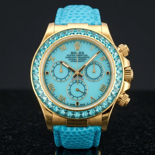 Gold-tone chronograph with a turquoise dial, gold Roman numerals and a bezel of light aqua-blue step-cut stones standing upright on polished black granite