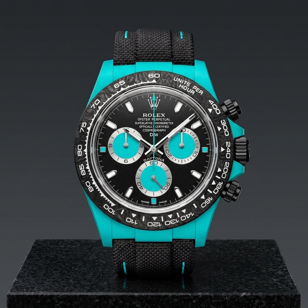 Turquoise-cased chronograph on a black woven strap with turquoise stitching, worn under a cuff