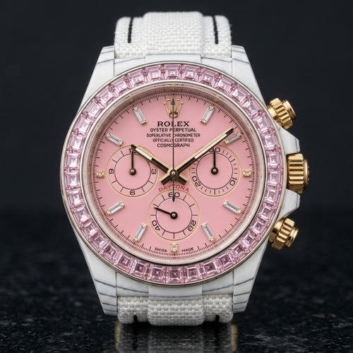 White carbon chronograph with a pale pink stone bezel and a pink dial, upright on polished black granite
