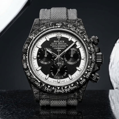 Forged-carbon chronograph with a black dial inside a white chapter ring, on pale stone