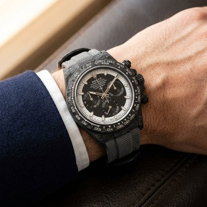 Forged-carbon chronograph on a grey woven strap, worn under a cuff