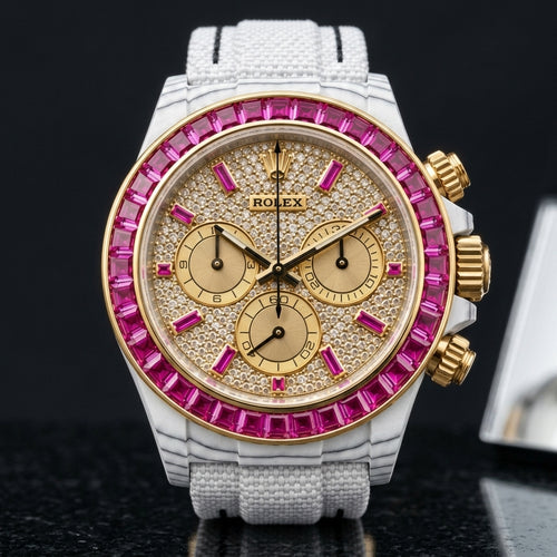 White carbon chronograph with a fuchsia stone bezel and a paved gold dial, upright on polished black granite