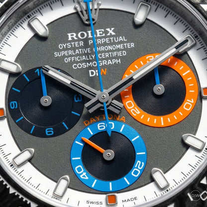 Macro of the grey dial showing the orange and blue counter rings and the blue hands