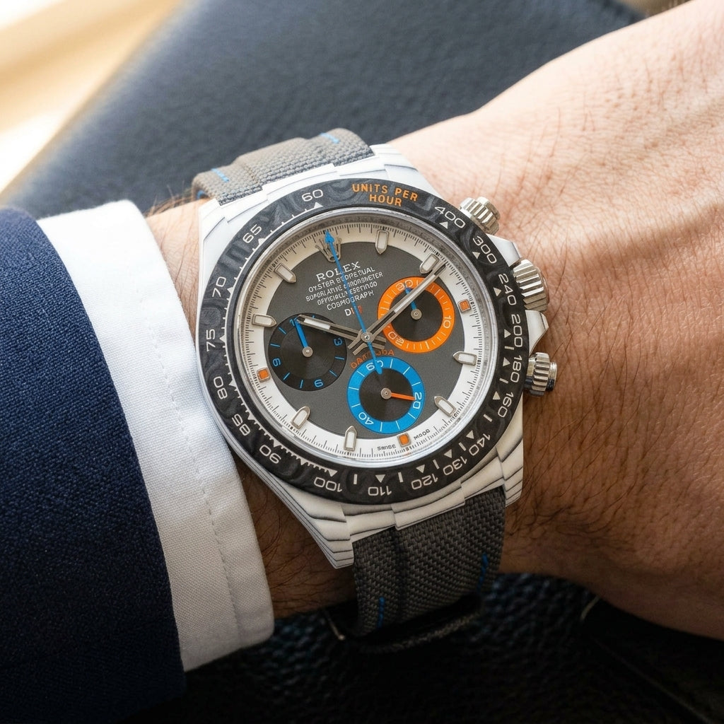 White CarboQuartz chronograph on a grey woven strap with blue stitching, worn under a cuff