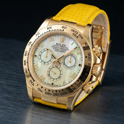 Gold-tone chronograph at a three-quarter angle on dark slate, its screw-down crown and fluted pushers beside a bright yellow lizard-grain strap