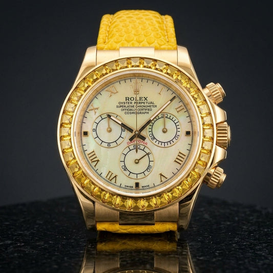 Gold-tone chronograph with a pale yellow mother-of-pearl dial, gold Roman numerals and a bezel of golden-yellow step-cut stones standing upright on polished black granite